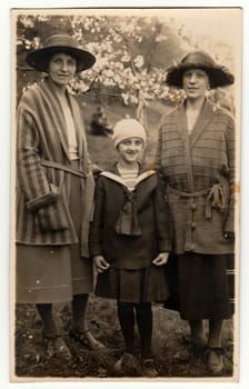 THE CZECHOSLOVAK REPUBLIC - CIRCA 1940s: Vintage photo shows elegant women with girl in the garden during spring time. . Black white antique photography.