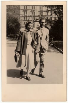 THE CZECHOSLOVAK SOCIALIST REPUBLIC - APRIL 27, 1949: Vintage photo shows a couple goes for a walk in the city park. Black white antique photo.