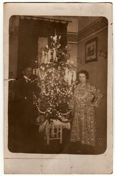 THE CZECHOSLOVAK REPUBLIC - CIRCA 1923: Vintage photo shows elderly couple next to the Christmas tree. Black white antique photo.