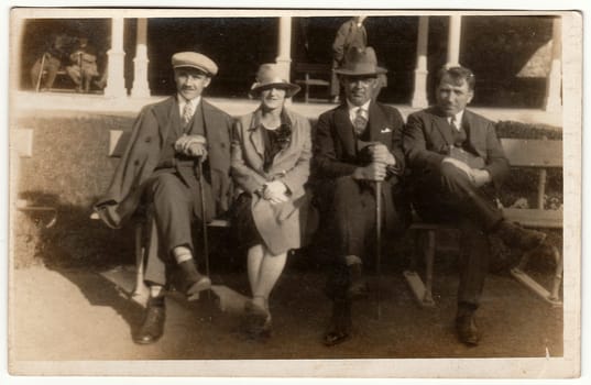 LUHACOVICE, THE CZECHOSLOVAK REPUBLIC - CIRCA 1940s: Vintage photo shows men and woman sit on a bench in spa resort. Black white antique photography.