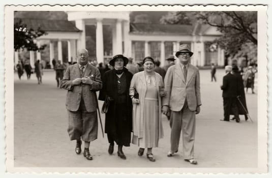 MARIANSKE LAZNE, THE CZECHOSLOVAK REPUBLIC - JULY, 1936: Vintage photo shows mature couples go for a walk in the spa resort. Black white antique photography.