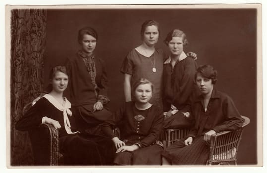 THE CZECHOSLOVAK REPUBLIC - CIRCA 1930s: Vintage photo shows girls pose at home. Some of them sit on the wicker armchairs. Antique black white photography.