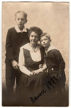 PRAGUE, AUSTRIA-HUNGARY - CHRISTMAS, 1917: Vintage photo shows mother with children (boys). Black white antique photography.