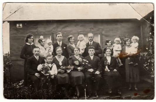 GERMANY - CIRCA 1940s: Vintage photo shows a big family poses behind house. Black white antique photography.