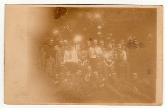 THE CZECHOSLOVAK REPUBLIC - CIRCA 1920s: Vintage photo shows a big group of young people pose outdoors. Black & white photography with sepia effect.