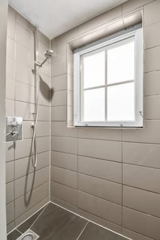 a bathroom with tile on the walls and shower head mounted to the wall, in front of a large window