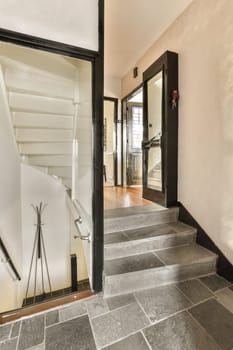 a hallway in a house with black and white tiles on the floor, an open door leading to another room