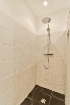 a shower with white tiles on the walls and black gre floor in a tiled bathroom stall, which is also used as a
