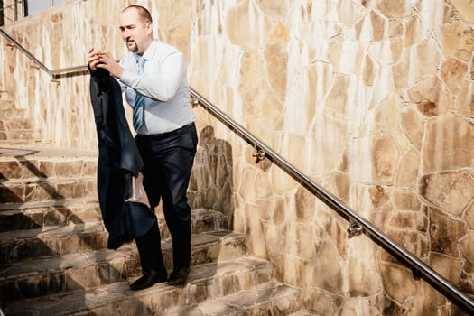 Portrait of a senior professional man in a suit with various problems. A middle-aged businessman with a briefcase descends the stairs.