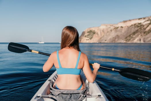 Woman in kayak back view. Happy young woman with long hair floating in transparent kayak on the crystal clear sea. Summer holiday vacation and cheerful female people relaxing having fun on the boat