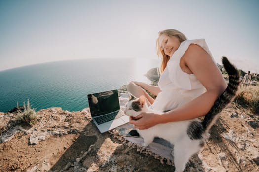 Woman sea laptop. Business woman in yellow hat working on laptop by sea. Close up on hands of pretty lady typing on computer outdoors summer day. Freelance, digital nomad, travel and holidays concept.