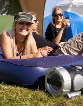 Camping crew. a young woman relaxing on a blow up mattress at an outdoor festival