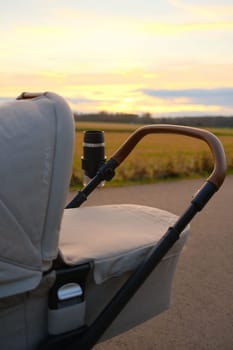 Nuna brand baby stroller near a field against sunset sky