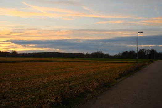 Field along a road against a scenic sunset sky in Meerbusch, Germany