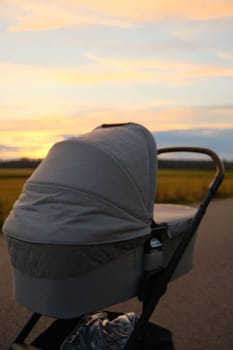 Nuna brand baby stroller near a field against sunset sky