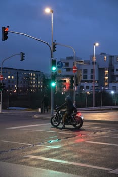 Motorcyclist with retro motorcycle standing in front of a green traffic light in Heerdt