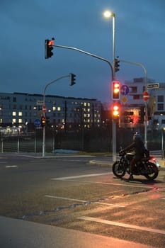 Motorcyclist with retro motorcycle standing in front of a green traffic light in Heerdt
