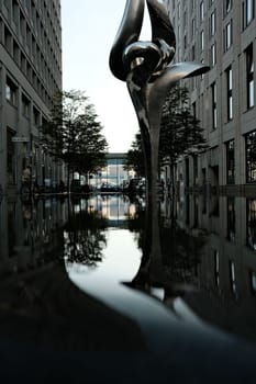 Vertical shot of the reflection of a sculpture in the water near Potsdamer Platz