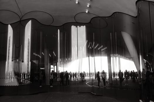 Grayscale view of people reflection on the curved wavy mirror facade on Elbphilharmonie in Hamburg, Germany