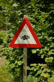 Vertical shot of a warning snake sign in the forest. Leogang, Salzburg, Austria.