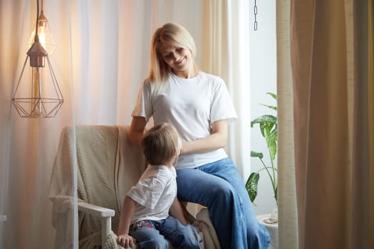 Happy loving family with mother and daughter in living room. Woman mom and small child girl playing and having convercation inside of home