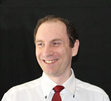 Young Caucasian man with shirt and tie with a broad smile. Black background