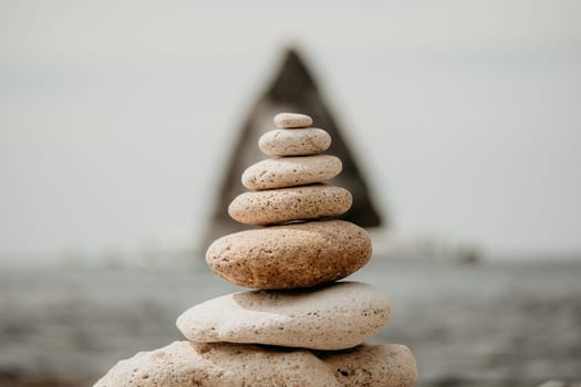 Pyramid stones on the seashore with warm sunset on the sea background. Happy holidays. Pebble beach, calm sea, travel destination. Concept of happy vacation on the sea, meditation, spa, calmness.