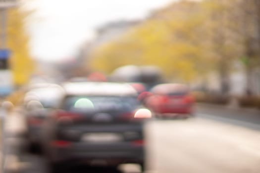 Autumn season bokeh background. Abstract city blur along the road with cars