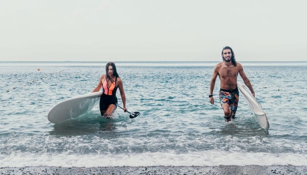 Sea woman and man on sup. Silhouette of happy young woman and man, surfing on SUP board, confident paddling through water surface. Idyllic sunset. Active lifestyle at sea or river