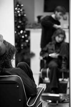 Beautiful young woman in modern hair salon. hairdresser checking hairstyle of caucasian girl