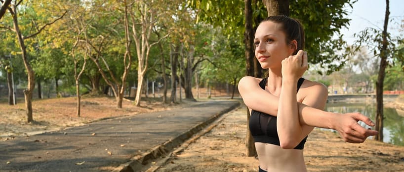 Gorgeous sporty caucasian woman in sportswear stretching body before running in the park. Healthy lifestyle concept.