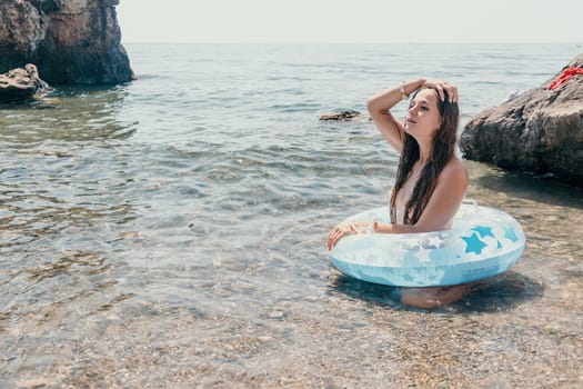 Woman summer sea. Happy woman swimming with inflatable donut on the beach in summer sunny day, surrounded by volcanic mountains. Summer vacation concept