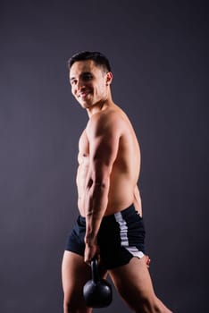 Hispanic male athlete working out with kettlebell on a grey background. Crossfit workout theme.