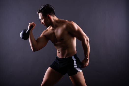 Hispanic male athlete working out with kettlebell on a grey background. Crossfit workout theme.