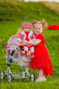 The girl plays with a doll in nature, holding her in her arms