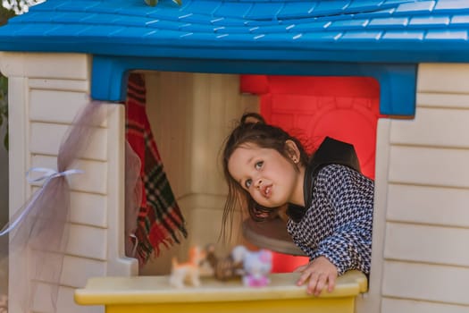 girl is playing in her little house, looking out the door