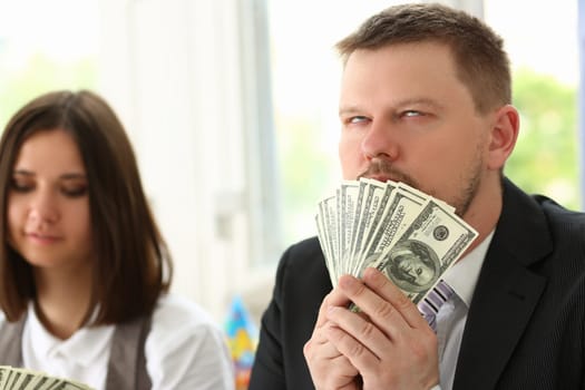 Man holds up dollars banknotes and enjoys success of financial income and growth. Emotion high from money concept