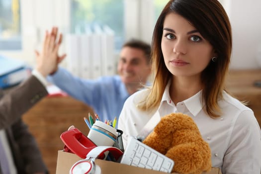 Sad dismissed woman against background of joyful colleagues partners in office. Stressed young lady having nervous breakdown after getting fired