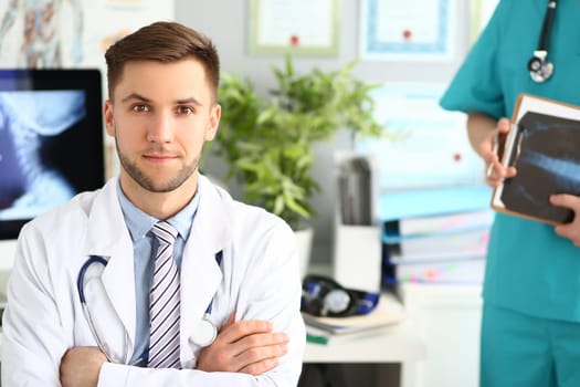 Portrait of young doctor in clinic with an assistant. Medical services and examinations of body concept