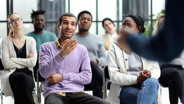 speaker addresses people sitting on chairs in a conference room