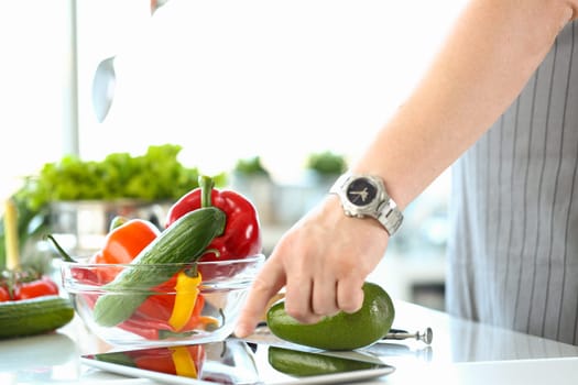 Chef following recipe on digital tablet preparing vegetable salad in kitchen. Online cooking course and recipe app