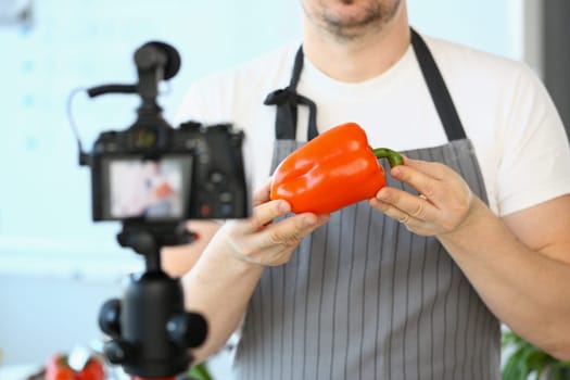 Food blogger creates healthy eating content and videos. Chef holds red pepper in hands and points to camera