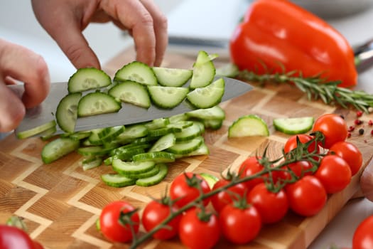 Cutting vegetables with knife for cooking on board. Cucumber tomatoes cooking salad