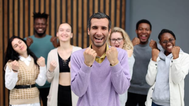Cheerful business colleagues clenching fists celebrating victory in office