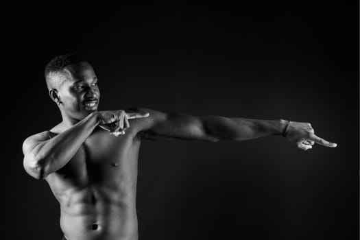 Athletic african american man topless, big muscles, a dark background studio