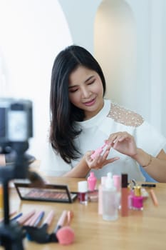 online trading business, a beautiful young woman working independently at home reviewing cosmetic products through the camera to customers to increase their interest in making a purchase decision.