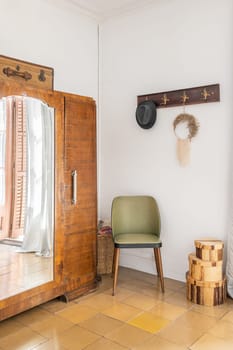 White room with stylish furniture wooden wardrobe with mirror, armchair and hanger with boxes and floor tiles. Rustic design concept in vintage style. Copyspace.