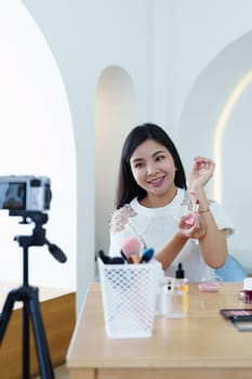 online trading business, a beautiful young woman working independently at home reviewing cosmetic products through the camera to customers to increase their interest in making a purchase decision.