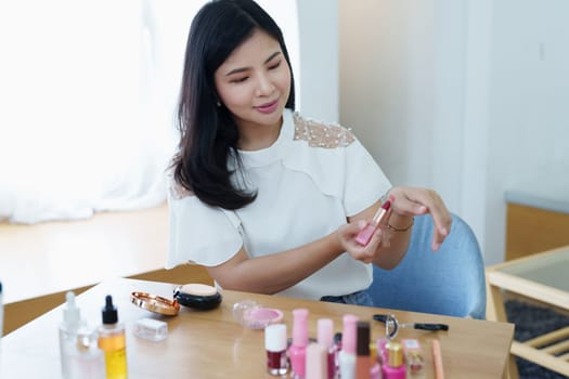 online trading business, a beautiful young woman working independently at home reviewing cosmetic products through the camera to customers to increase their interest in making a purchase decision.