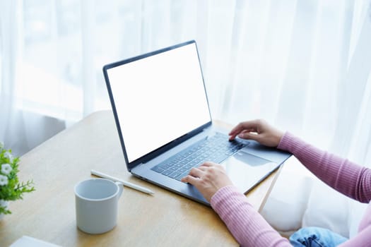 A business woman using blank white screen laptop computer with on her desk.